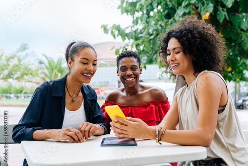 Three mixed race hispanic and black women bonding outdoors and meeting in a bar cafè photo