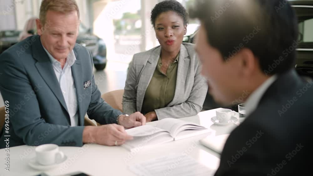 Couple choosing car color from sample with salesman in dealership Couple choosing car color from sample with salesman in dealership