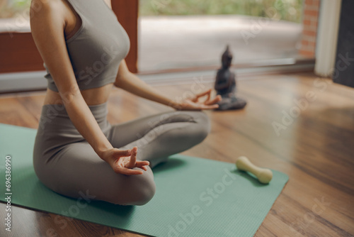 Close up of woman is practicing yoga and meditation at home sitting in lotus pose on mat
