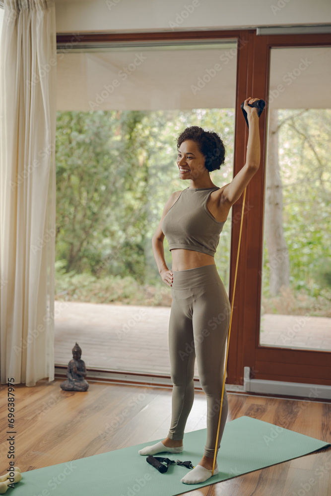 Sporty woman in headphones exercising with a sports elastic band at home Sporty woman in headphones exercising with a sports elastic band at home
