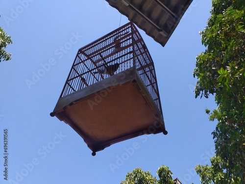 Bird house hanging on roof with blue sky background