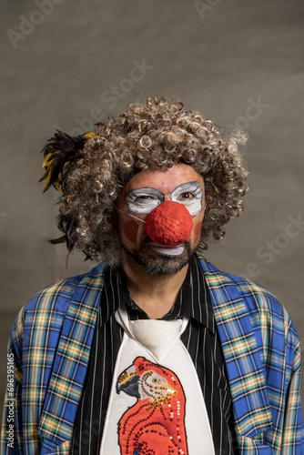 A cheerful curly-haired clown is squinting. Portrait in profile close-up . The clown in the parrot tie