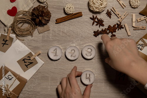 Unrecognizable young woman paint numbers on tea candles. Female making homemade advent calendar Made with your own hands step by step DIY crafts do it yourself. Preparation to christmas concept photo