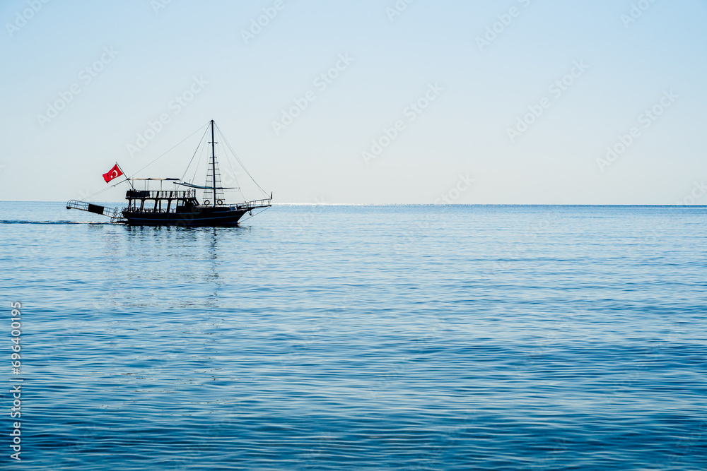 Silhouette of a boat floating on the Mediterranean sea off the coast of Cirali, Turkey Silhouette of a boat floating on the Mediterranean sea off the coast of Cirali, Turkey