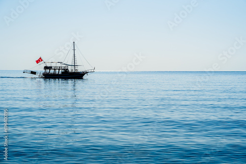 Silhouette of a boat floating on the Mediterranean sea off the coast of Cirali, Turkey