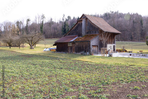 Old wooden barns on a green meadow, benches and tables in front of the house, ideal for photo compositions, during the day, cloudy sky without people
