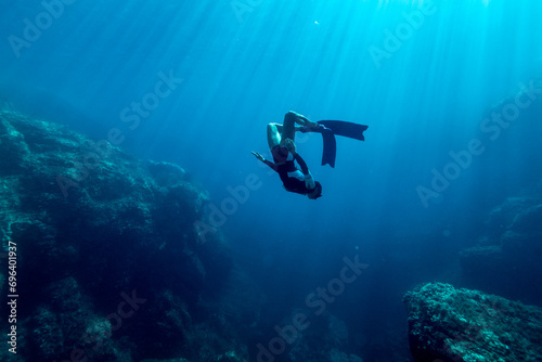 Girl with a sporty body practicing free diving in the crystal clear waters of Sardinia