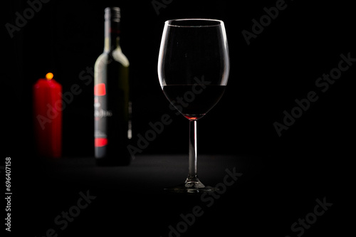 Red wine bottle, glass of wine and candle