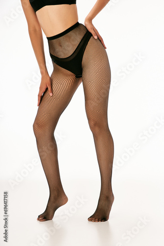 cropped photo of woman in black underwear and stylish fishnet tights posing on white background