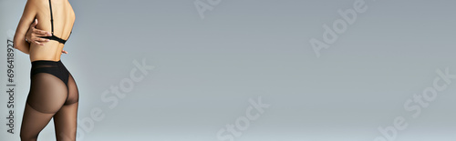 Fotografía banner, cropped view of slim woman in black pantyhose and bra standing on grey b