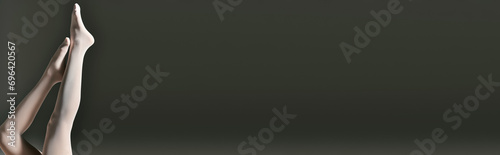 cropped banner of woman in sheer white pantyhose posing with raised legs on dark grey background photo