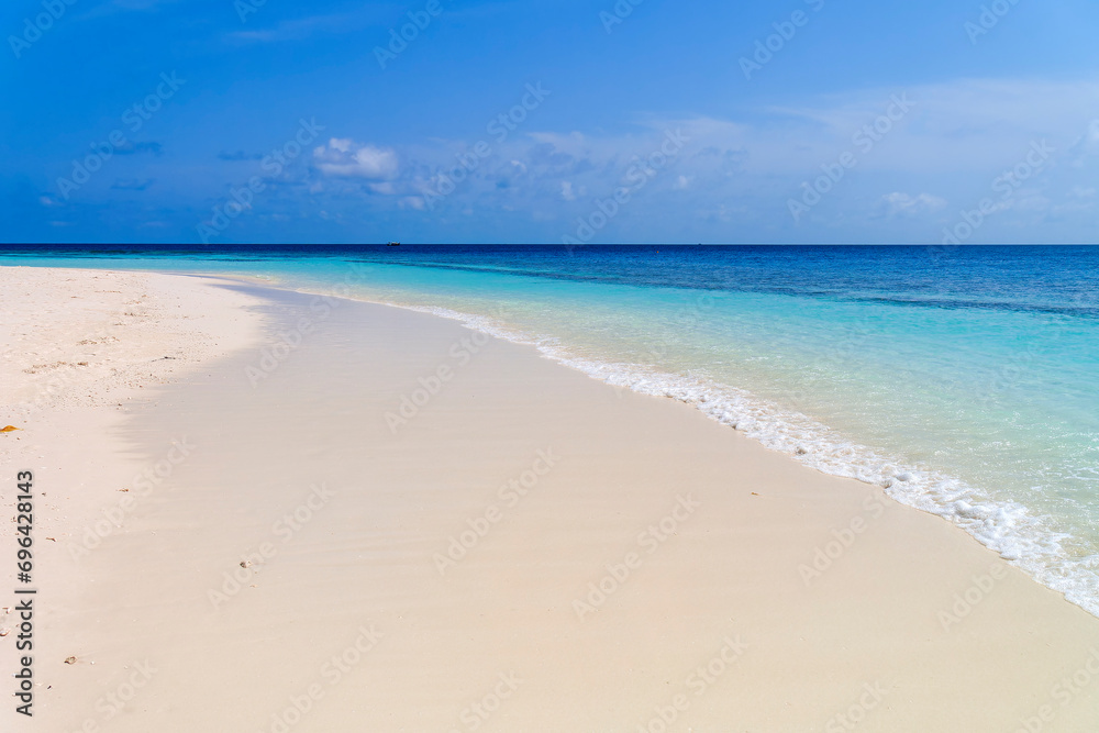 Wide sandy beach with smooth wave in front of blue ocean, peaceful relaxing scene