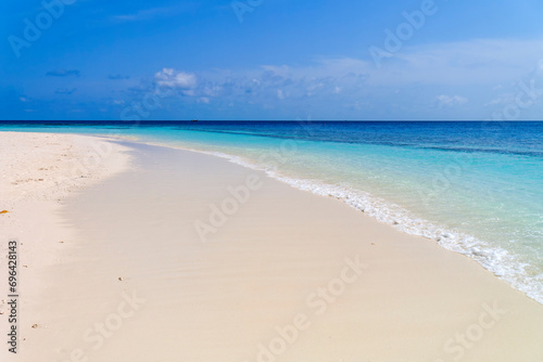 Wide sandy beach with smooth wave in front of blue ocean  peaceful relaxing scene