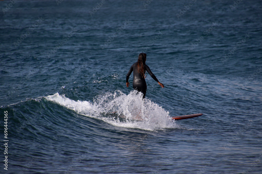 Surfer girl riding the waves of the Atlantic ocean on longboard Surfer girl riding the waves of the Atlantic ocean on longboard