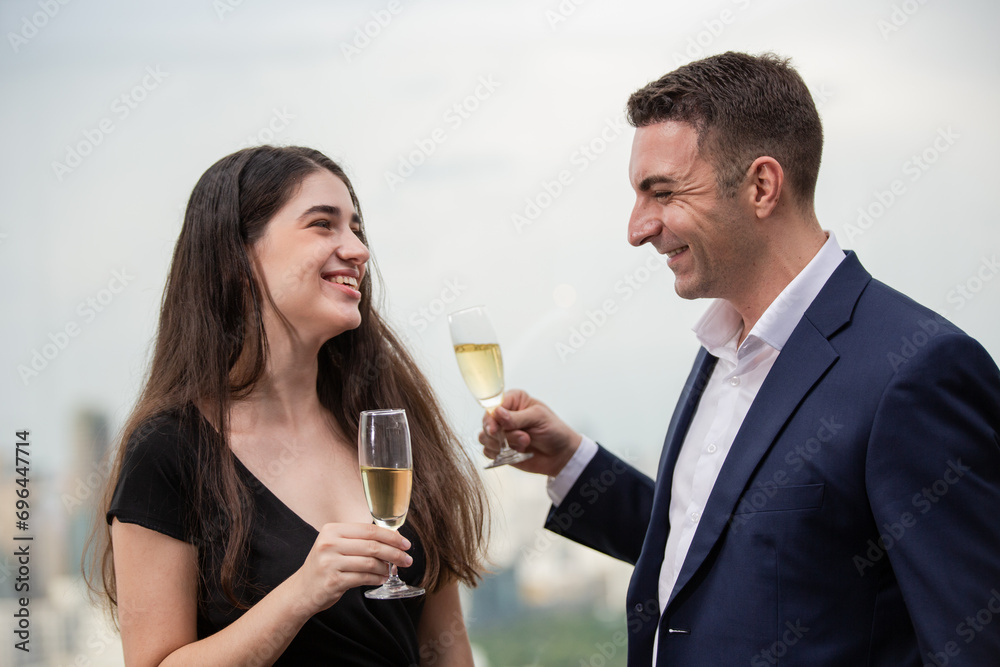 Happy businesspeople enjoy talking together at the office event. Man and woman with champagne smiling and laughing at business meeting party. People flirting while joining corporate activities Happy businesspeople enjoy talking together at the office event. Man and woman with champagne smiling and laughing at business meeting party. People flirting while joining corporate activities