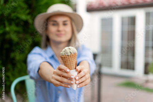 Woman holding melting ice cream waffle cone in hands on summer and showing to camera