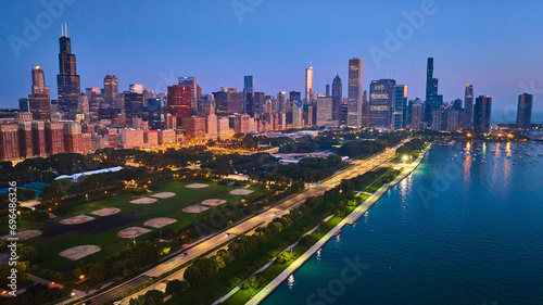 Aerial Chicago park at night with city lights and sunset glow over buildings with Lake Michigan, IL