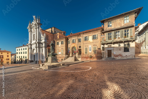 Bra, Cuneo, Italy - The town hall and parish church Sant' Andrea Apostolo in Piazza Caduti per la Liberta, Coblestone with the statue of St. Joseph Cottolengo photo