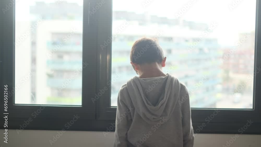 Child alone in front of a large window with his back to himself. Depression, childhood abuse, bullying and mental health disorder and autism. Child alone in front of a large window with his back to himself. Depression, childhood abuse, bullying and mental health disorder and autism.