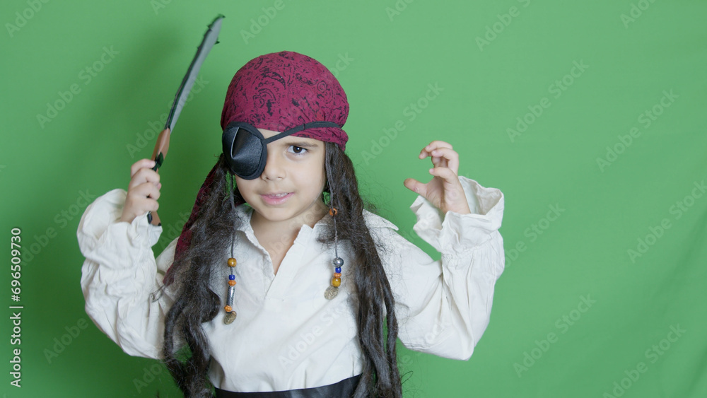 Adorable kid pirate with long hair and eye patch pissing with angry pirate face over green background. High quality photo Adorable kid pirate with long hair and eye patch pissing with angry pirate face over green background. High quality photo