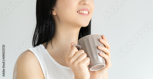 マグカップで飲み物を飲む白い服の若い女性