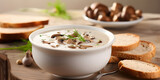 Mushroom creme puree soup in a white bowl with bread sliced, blurry dark background 