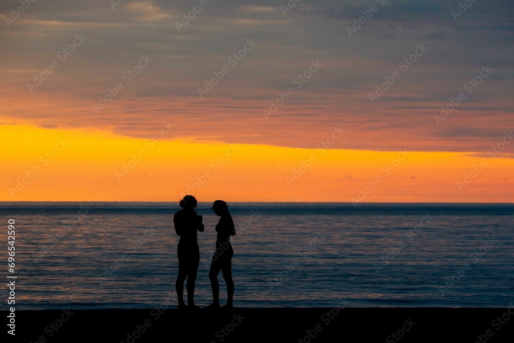 Two silhouettes on the background of a yellow-red sunset