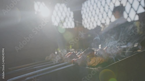 Sun rays fall on fried barbecue on grill against man resting in gazebo. Concept of rest and cooking meat. Place for a comfortable stay photo