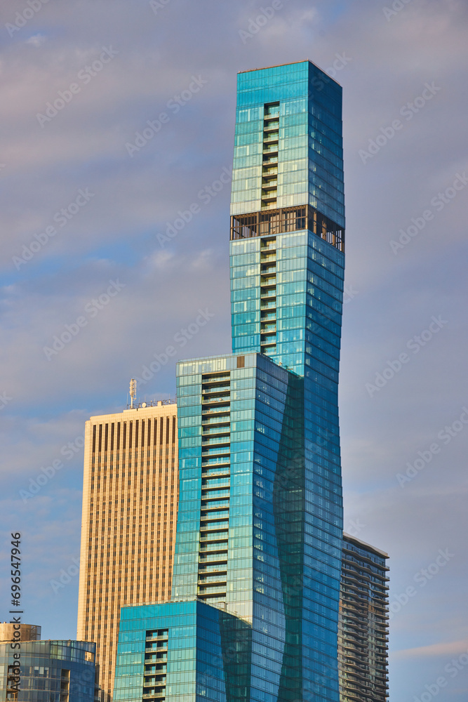 Blue skyscraper with multiple tiers in Chicago with golden light in summer and purple tinged sky Blue skyscraper with multiple tiers in Chicago with golden light in summer and purple tinged sky