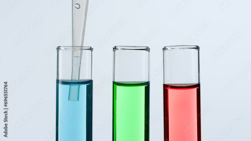 Concept of science and biotechnology. Closeup of laboratory utensils on white background. Test tubes filled with blue, green and red liquid, scientist pipetting blue liquid from test tube. Slow motion Concept of science and biotechnology. Closeup of laboratory utensils on white background. Test tubes filled with blue, green and red liquid, scientist pipetting blue liquid from test tube. Slow motion
