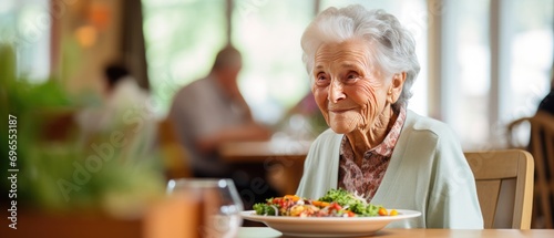 Elderly woman smiling at table with healthy meal in senior care facility. Nutrition for aging adults. photo