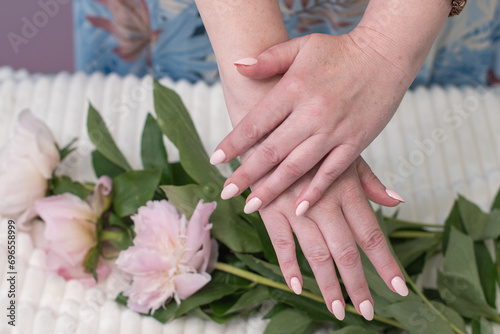 female hands with a beautiful peach manicure design, color 2024, pastel colors, delicate spring dewy peonies in the hands of a model, high quality photo