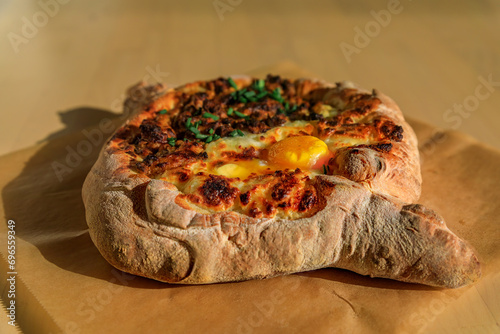 Closeup of a boat shaped Georgian flat bread or Adjaruli khachapuri stuffed with cheese with an egg at a restaurant in Seattle, Washington, USA photo