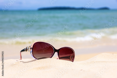 Sunglasses on a sand of tropical beach. Defocused view to sea waves