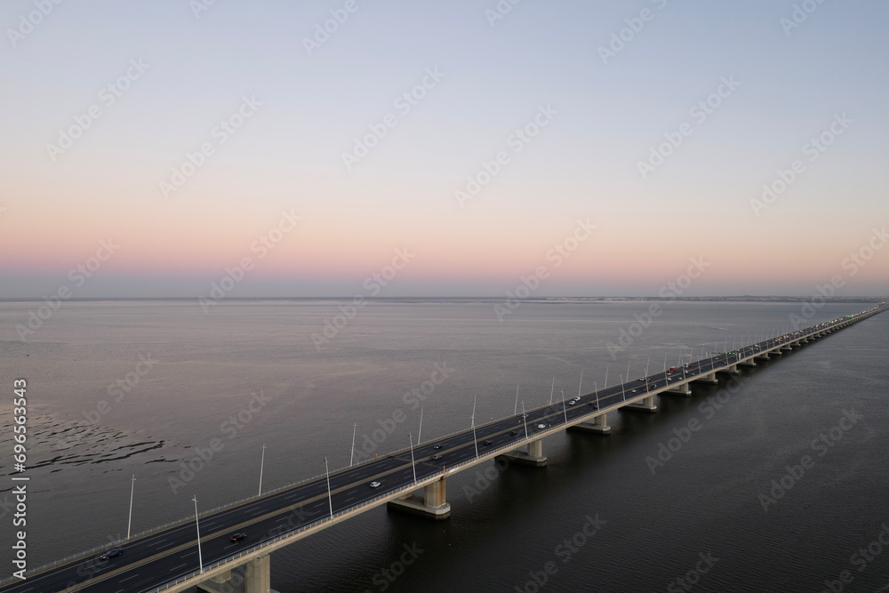sunset over the ocean and second longest in europe bridge with cars driving vasco da gama in lisbon portugal