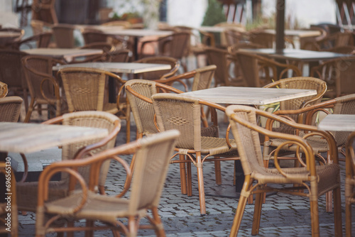 Coffeehouse cafe restaurant terrace. Wooden chairs and tables. Outdoor terrace concept. Shallow focus. Copy space. Old fashioned empty cafe terrace with vintage chairs and tables. Loft style cafe. © Cristina