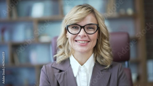 Portrait mature businesswoman female teacher, mentor, tutor looking at camera sitting in office classroom at a workplace indoor. Middle aged woman in glasses entrepreneur accountant boss smile photo