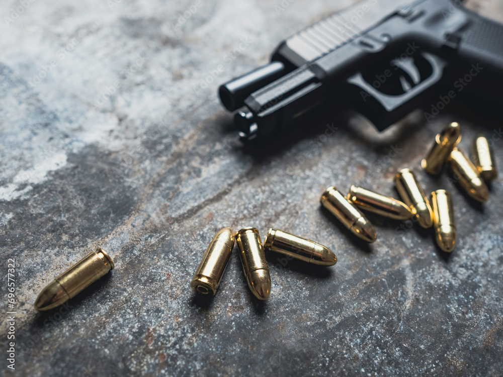 Hand gun with ammunition on dark background. 9 mm pistol military weapon and pile of bullets ammo at the metal table. Hand gun with ammunition on dark background. 9 mm pistol military weapon and pile of bullets ammo at the metal table.