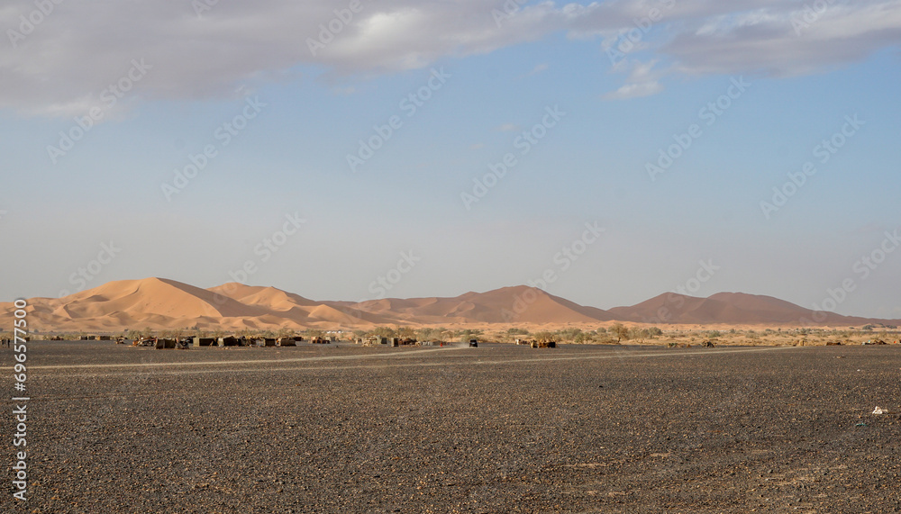 A wide view of a nomadic settlement and sand dunes of the Sahara Desert, Morocco.