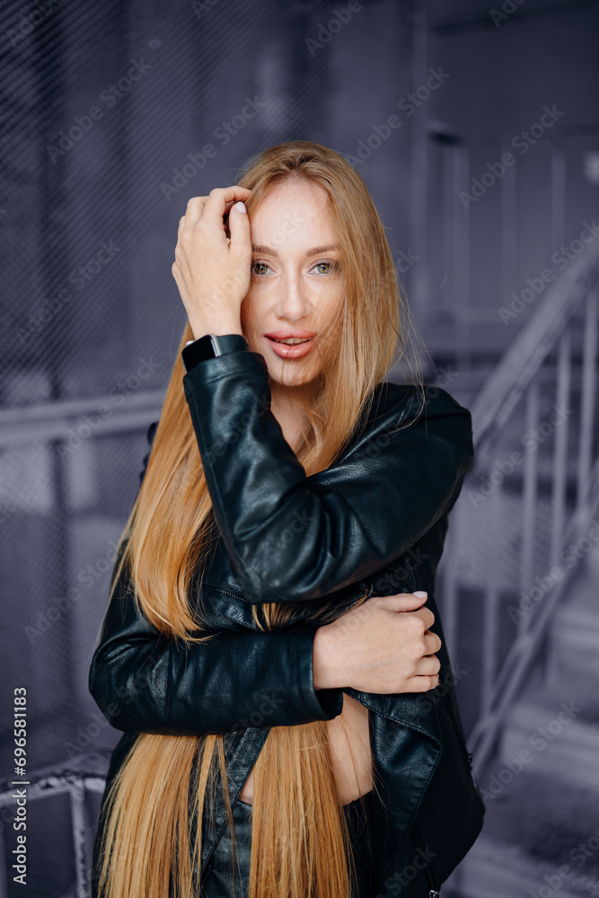 Beautiful young red-haired long-haired woman in black leather shirt