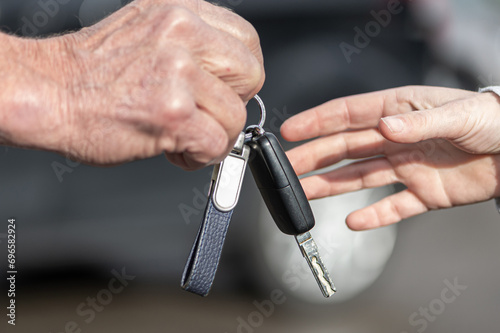 Canvas Print A businessman hands over a car key to a woman in front of a blurred car