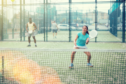 Portrait of cheerful woman paddle tennis player during friendly doubles couple match with male friend at court