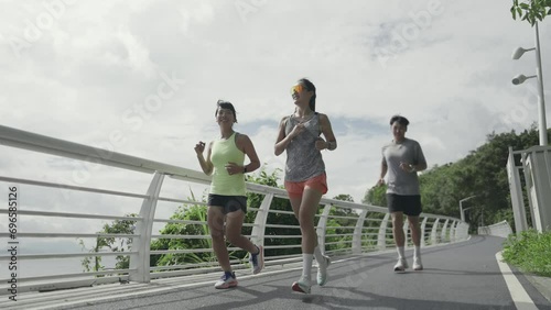 three happy young asian people jogging running exercising outdoors in park by the sea