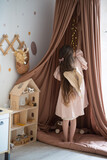girl with wings plays with a doll house