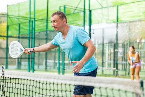 Male padel tennis player training on court. Man using racket to hit ball. © JackF