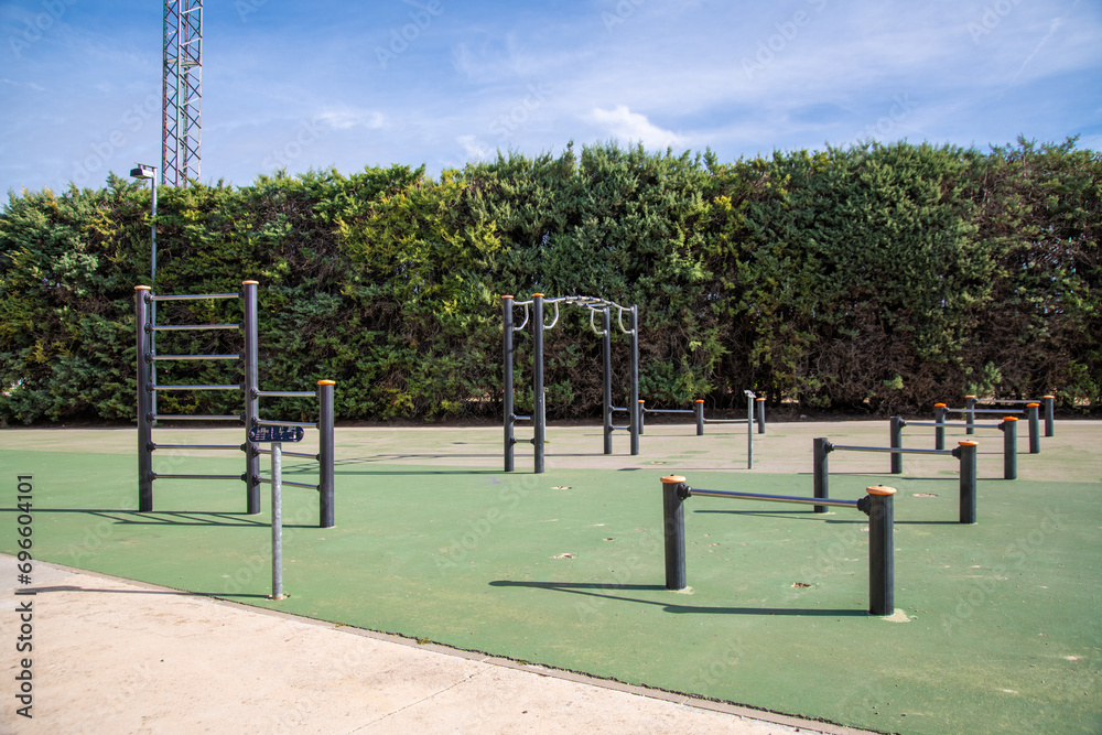 Public outdoor fitness facility with green artificial turf and pull-up bars