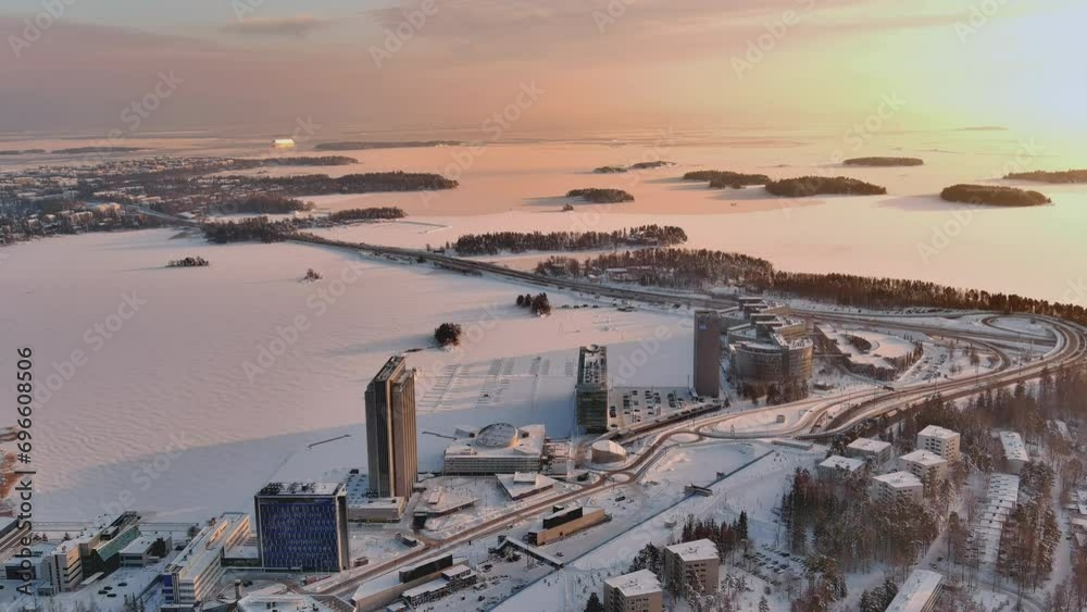 Espoo.Finland-February 3.2022: Aerial shot of the cityscape of Keilaranta in Espoo Finland during wintertime. Frozen sea. Different buildings. Snowy city. Drone slowly moving backwards.