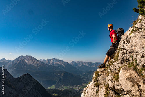Male climber on the top of the mountain looking at the landscape, with helmet