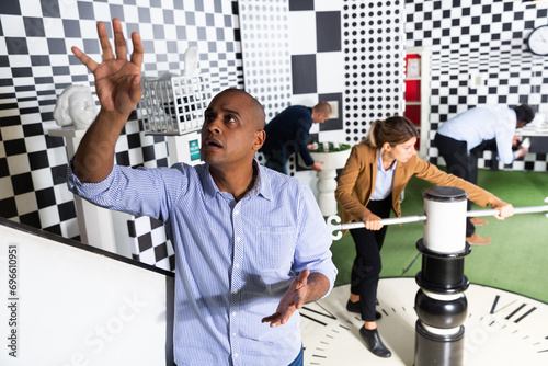 Young adult man trying to solve puzzles to get out of escape room, reaching for next key photo