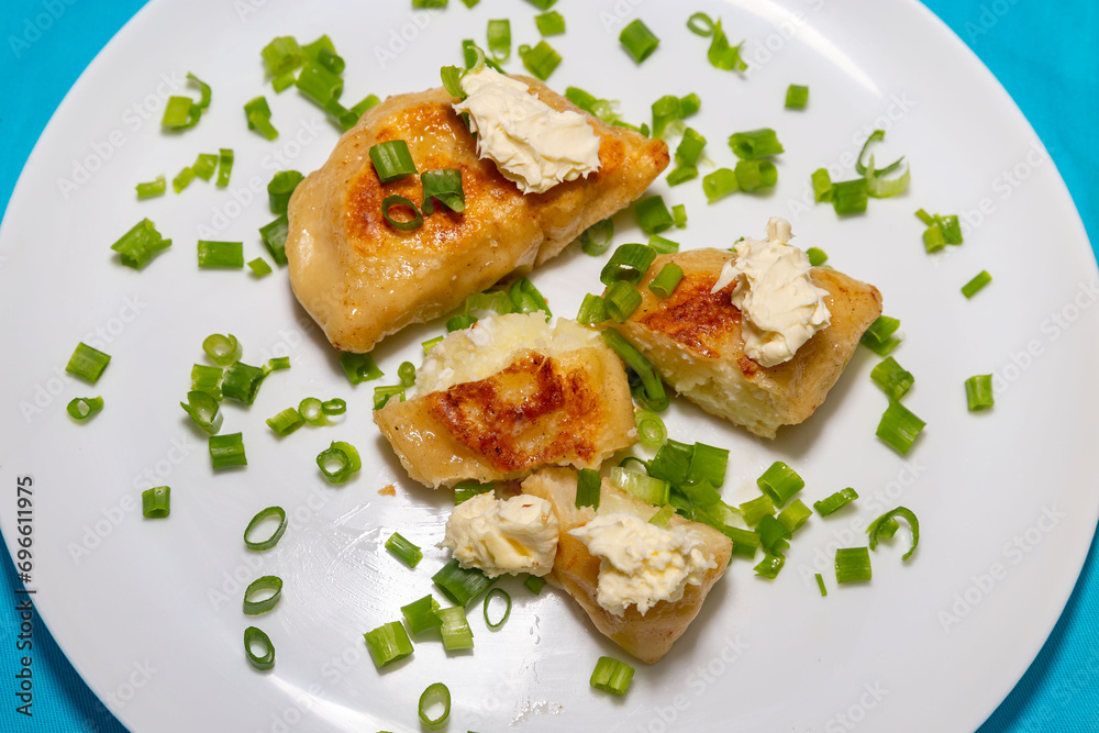Fried pieroguis Ukrainian traditional food, on white plate on tablecloth decorated with typical Ukrainian embroidery. With cream and fresh chives in fine details. Prudentópolis PR Fried pieroguis Ukrainian traditional food, on white plate on tablecloth decorated with typical Ukrainian embroidery. With cream and fresh chives in fine details. Prudentópolis PR